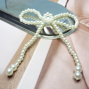 Detail of elegant faux pearl bow with long tassels for DIY craft and garment decor