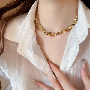 Dettaglio della collana dorata con paillettes a cuore indossata su una camicia bianca
