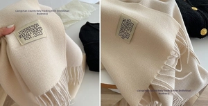 Detail of cream cashmere-like scarf showing thick knit texture and long fringe edges