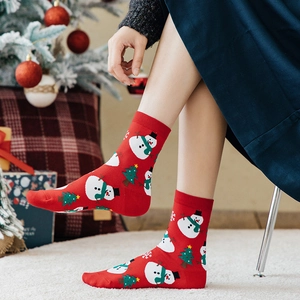 Festive red Christmas socks with snowman and reindeer patterns worn by a model