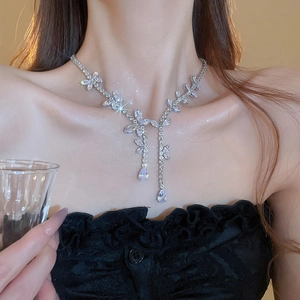Close-up of a silver necklace featuring leaf and water drop zircon charms on a model