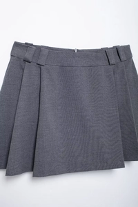 Detail view of grey pleated mini skirt featuring belt loops and a hidden back zipper