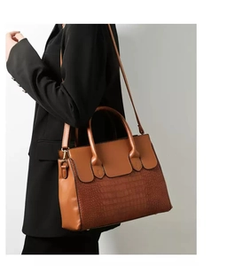 Detailed view of brown tote bag with smooth leather and crocodile pattern texture