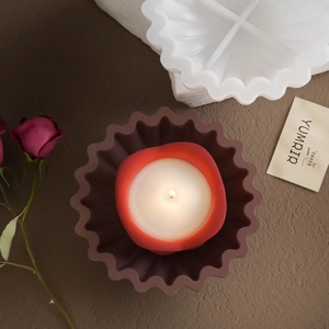 Bovenaanzicht van een geribbelde siliconen vorm met een brandende kaars op een houten tafel