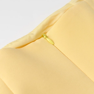 Détail de l'ensemble plissé jaune montrant une fermeture éclair invisible discrète