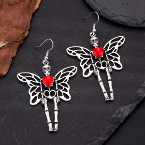 Detail of silver skull butterfly earrings with red heart gems on dark stone base
