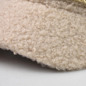 Close-up of beige teddy fleece fabric with elegant gold chain detail on fashion hat