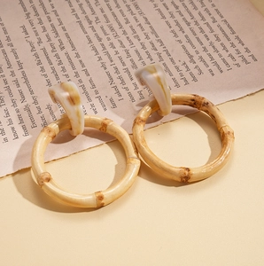 Detail of bamboo hoop earrings with marble pattern geometric stud on vintage book