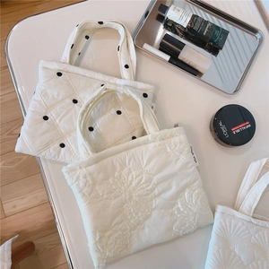 Dettaglio di borsa trapuntata bianca con ricamo floreale e motivi a pois neri