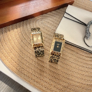 Detail of square gold quartz watches with leopard print mesh bands on textured surface