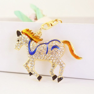 Sparkling crystal running horse keychain with orange enamel details on white surface