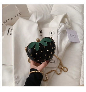Detail of black strawberry chain bag with gold studs and metallic shoulder strap