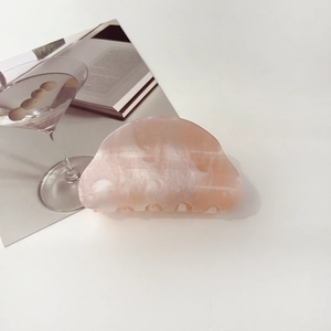 Detail of pink marble pattern acrylic hair claw clip next to a cocktail glass