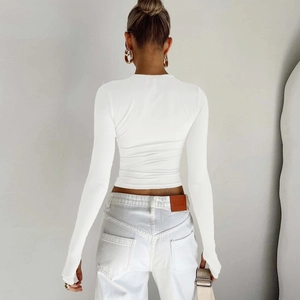 Detail view of white long sleeve crop top with thumb holes and slim fit design