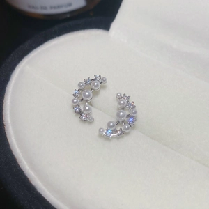 Macro shot of silver crescent earrings with white pearls and zircons in a jewelry box
