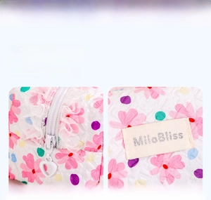 Detail of floral makeup bag featuring white lace trim and a heart-shaped metal zipper
