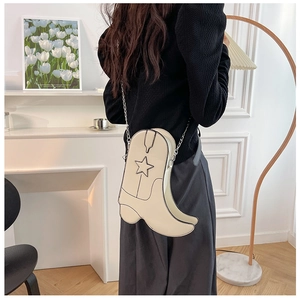 Detail view of cream cowboy boot shaped crossbody bag with star motif on a metal chain