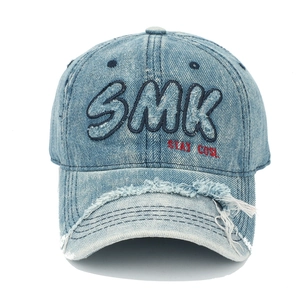 Détails de broderie SMK sur casquette en jean bleu clair délavé avec bords usés