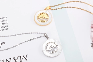 Detailed view of gold and silver hollow tree of life pendants with mother of pearl inlay