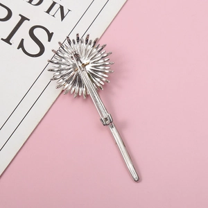 Silver dandelion brooch with detailed back pin mechanism on minimalist pink background