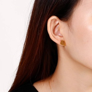 Detail shot of heart-shaped hollow gold earrings with delicate scroll pattern on model