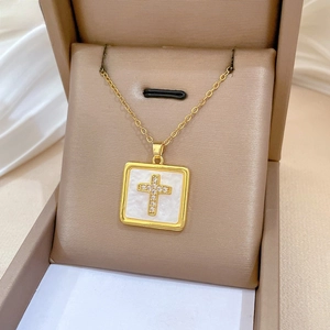 Close-up of golden square pendant with sparkling cross on luxury jewelry box