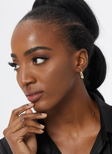 Macro shot of chunky gold-plated C-shaped hoop earrings with a high-polished finish
