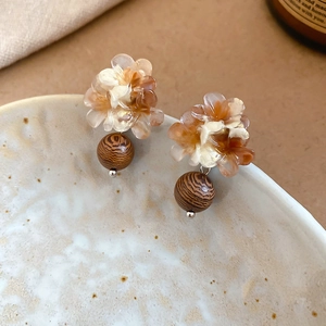 Détail de boucles d'oreilles fleurs en résine vintage avec perles en bois brun