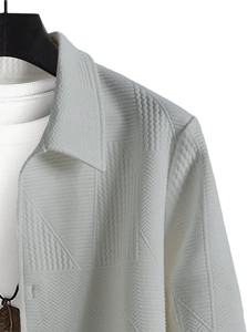 Detail of white casual jacket featuring textured geometric jacquard patterns and lapel collar