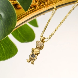 Détail d'un collier chaîne en or avec pendentif garçon serti de cristaux bleus