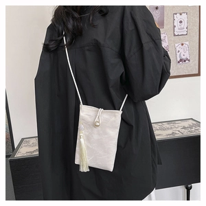 Détail du petit sac blanc plissé avec fermoir perle et pampille décorative en soie