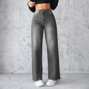 Detail van de donkergrijze jeans met hoge taille, wijde pijpen en onafgewerkte zoom op model