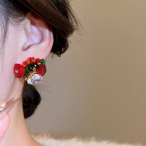 Close-up of handmade floral beaded stud earrings with red and green crystal details