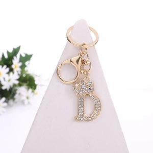Golden letter D keychain with crown and sparkling crystals on a white display