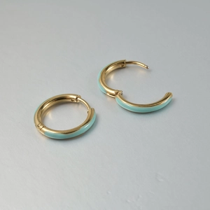 Detail of gold-plated hoop earrings with turquoise enamel inlay and hinged closure
