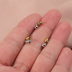 Macro shot of gold and silver stainless steel beads for jewelry making on a finger