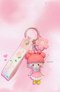 Close-up of pink Sakura girl keychain with floral accessories and printed wrist strap