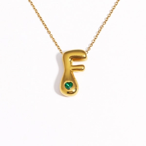 Detail of 18k gold plated bubble letter F pendant with a green heart gemstone