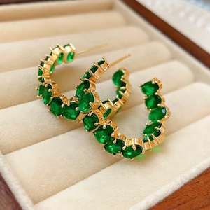 Orecchini a cerchio a C dorati con cristalli verde smeraldo in design di lusso