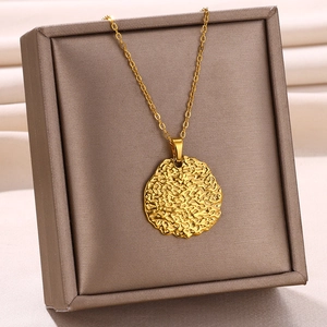 Gros plan détaillé du collier en acier doré avec pendentif lave texturé sur présentoir