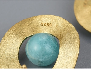 Macro shot of S925 sterling silver earring with blue stone and golden matte texture