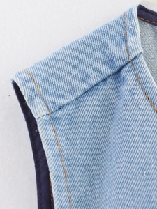 Detailed close-up of light blue denim vest shoulder with contrast orange stitching