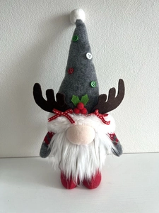 Close-up of handmade Christmas gnome with elk antlers and long plush white beard
