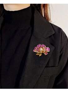 Macro view of purple enamel peony brooch with white pearl and sparkling crystals