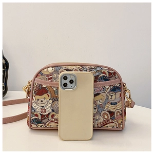 Detail of cartoon bear jacquard pattern and pink trim on shell-shaped canvas crossbody bag