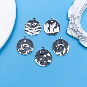 Five black and white enamel landscape pendants featuring wave, mountain and forest motifs