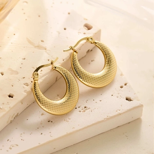 Gros plan de boucles d'oreilles créoles en acier titane plaqué or 18 carats avec texture
