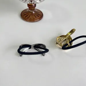 Minimalist metal hair ties with gold heart and silver bow accents on black elastic ropes