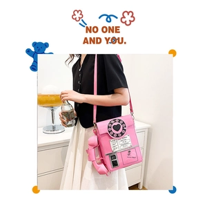 Close-up of creative pink retro telephone shaped crossbody bag with rotary dial details