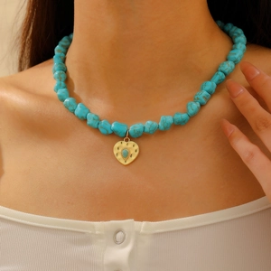 Detail of bohemian turquoise beaded necklace with gold heart pendant on model